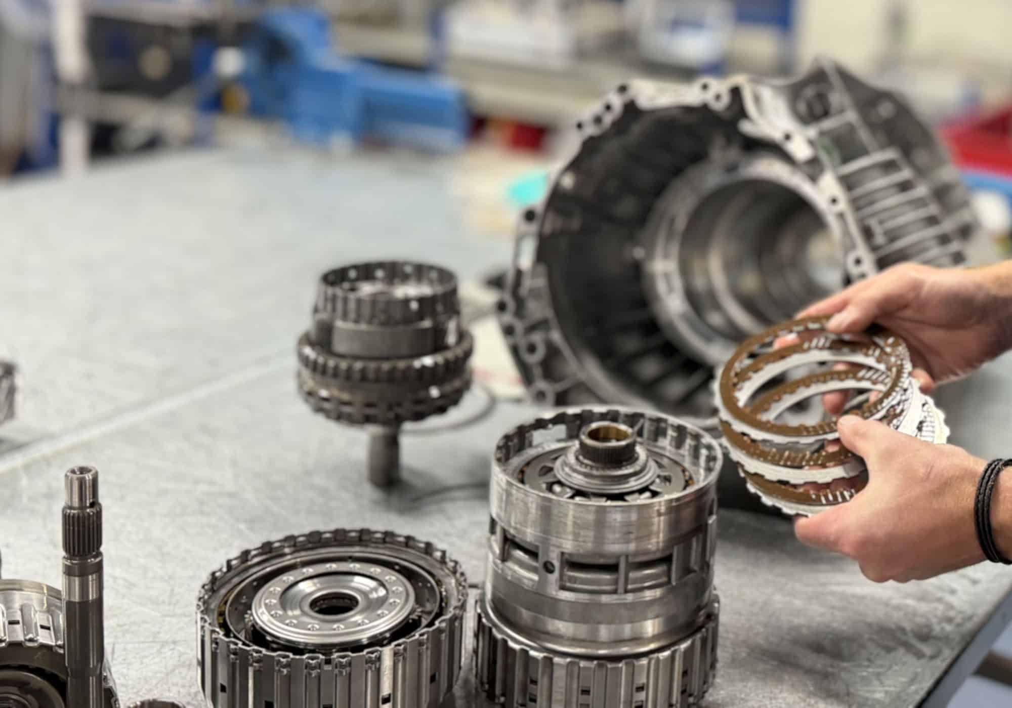 Automatic gearbox components including gears and clutch packs laid out on the workbench at Ganzeboom