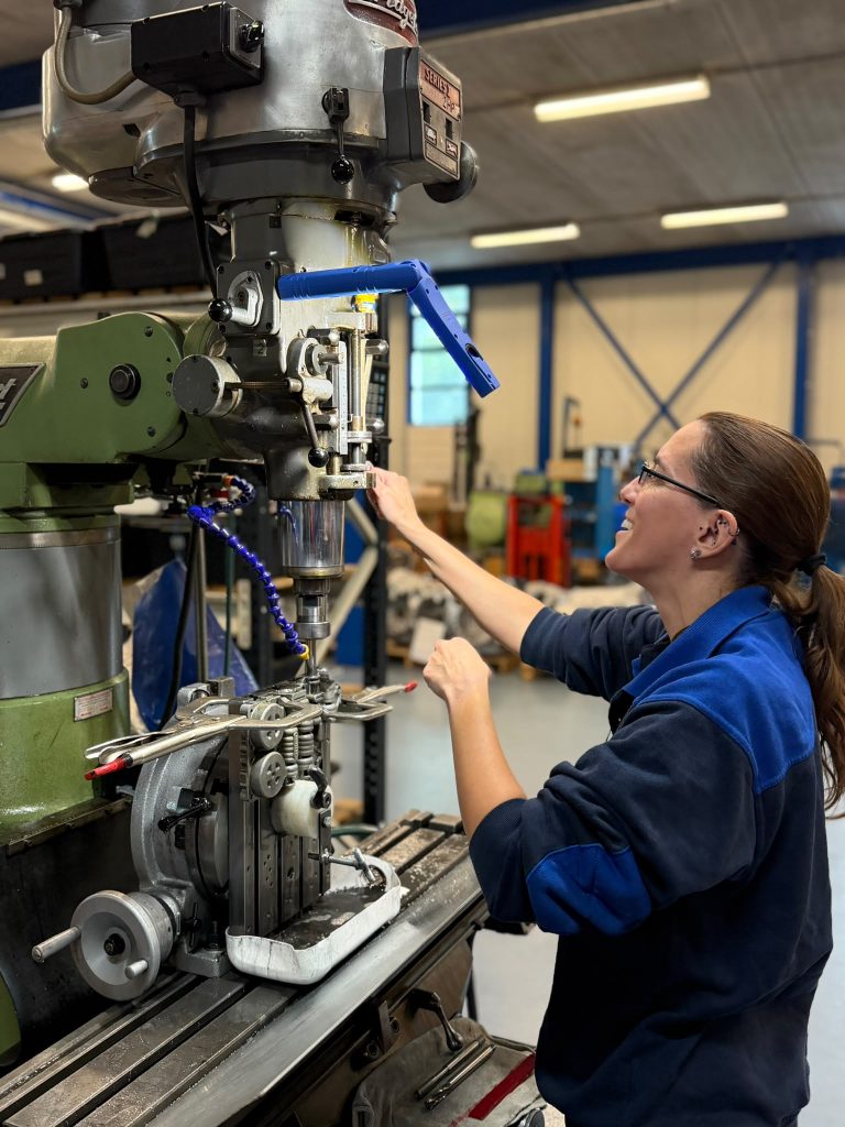 A technician machining a valve body on a milling machine in the Ganzeboom remanufacturing workshop.